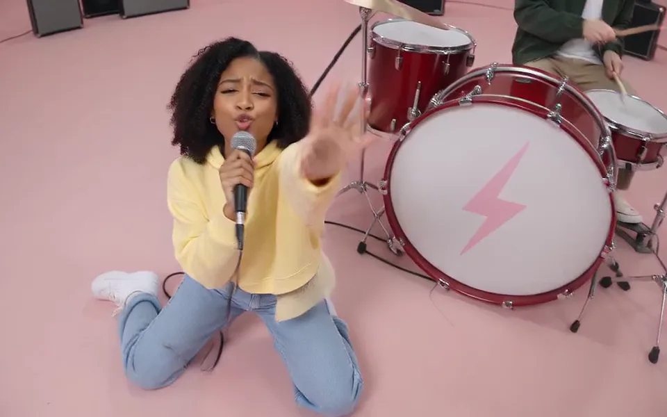 Frame from our APT. demo: the singer kneels by the red drum kit and sings into a microphone.