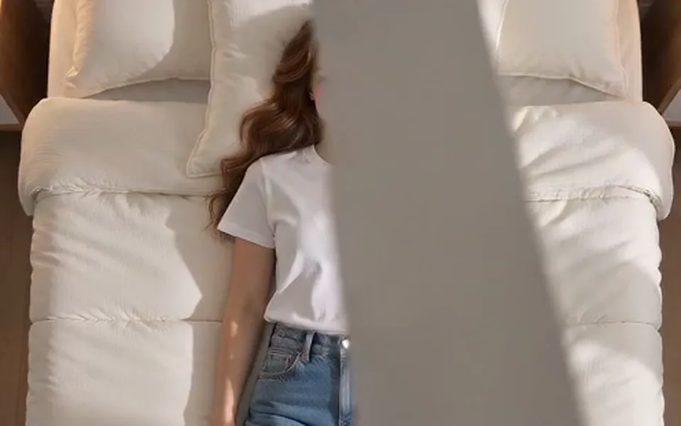 Frame from our demo: she lies in a grey hoodie, one arm behind her head.